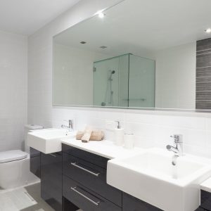 Modern twin bathroom with sinks, toilet and shower.